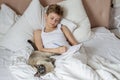 Cute handsome blonde boy lying in white bed and drawing. Boy smiling and playing with cat. Relax time Royalty Free Stock Photo