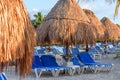 Morning tropical sandy beach with straw umbrellas and lounge chairs.