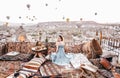 Morning view in Cappadocia. Terrace view in Goreme woman with hot air balloons and carpets