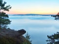 Morning view over rock and fresh green trees to deep valley full of light blue mist. Dreamy spring landscape within daybreak Royalty Free Stock Photo