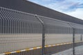 Morning winter frost on the steel grating fence made with wire on blue sky background. Sectional fencing installation. Royalty Free Stock Photo