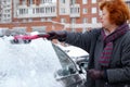 A woman cleans snow from the car