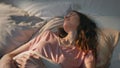 Morning woman lying asleep in sunlight closeup. Peaceful girl waking up in bed. Royalty Free Stock Photo
