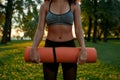 Morning workout outdoors. Cropped shot of a woman wearing sport clothes holding yoga mat while exercising in the morning Royalty Free Stock Photo