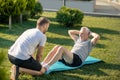 Young brown-haired male helping mature grey-haired male with sit ups