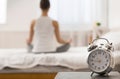 Morning yoga. Alarm clock standing on bedside table