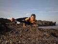 Morning yoga on the beach. Slim Asian woman practicing Astavakrasana. Eight-Angle Pose. Hand-balancing asana. Strong hands. Royalty Free Stock Photo