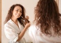 Morning of young African-American woman brushing hair near mirror Royalty Free Stock Photo