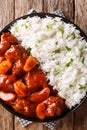 Moroccan beef stew with apples in tomato sauce served with rice closeup on a plate. Vertical top view