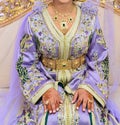 A Moroccan bride sits on the wedding chair in the traditional Moroccan dress. The caftan