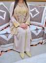 Moroccan bride wearing a Moroccan caftan sitting on a Moroccan sofa.