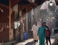 Fez, Morocco - December 07, 2018: Moroccan lady with her daughter walking through a passage of the fez medina with rays of light