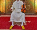 A Moroccan musician wearing a Moroccan djellaba plays the violin.