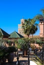 Moroccan Riad with flowers, palm trees, original lamp and view of the mosque of al-Koutoubia. Marrakech, Morocco Royalty Free Stock Photo