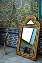 A Moroccan rifle with an old mirror next to a wall of traditional Moroccan zellij