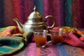 moroccan teapot with colorful tea glasses on patterned cloth