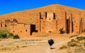 Moroccan woman carying a big bag with herbs with kasbah