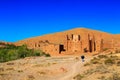 Moroccan woman carying a big bag with herbs with kasbah