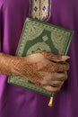 Moroccan woman with henna painted hands holding a koran