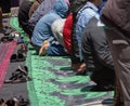 Moroccans praying in ramadan on green carpet, barefoot muslims