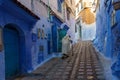 Morocco. Chefchaouen. An old man dressed in a bournous walking in a blue street of the medina Royalty Free Stock Photo