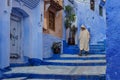 Morocco. Chefchaouen. An old man dressed in a bournous walking in a blue street of the medina Royalty Free Stock Photo