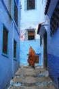 Morocco. Chefchaouen. An old man dressed in a bournous walking in a blue street of the medina Royalty Free Stock Photo