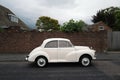 classic vintage car, A white Morris Minor 1000 parked in front of a red brick road on a residential  street Royalty Free Stock Photo