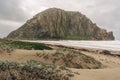 Morro Bay beach on a stormy day. Morro rock, sand dunes with native plants, and a cloudy sky Royalty Free Stock Photo