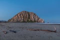 Morro Rock, Morro Bay. Beach with driftwood in foreground. Ocean to the side. Royalty Free Stock Photo