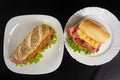 Mortadella, lettuce and cheese sandwiches and pepper and mustard sauce on white plates on a table with black towel, Top view Royalty Free Stock Photo