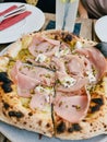 Mortadella pizza cut into several pieces stands on a table in a restaurant