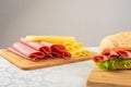 Mortadella sandwich, lettuce, tomato and cheese on a polished board and slices of mortadella and cheese next to it on a cold board