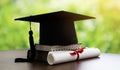 Mortar board with degree paper and books on wood table.