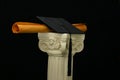 Mortar board and diploma on pedestal - black Royalty Free Stock Photo