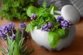 Mortar with fresh lavender flowers, herbs and pestle on wooden table, closeup Royalty Free Stock Photo