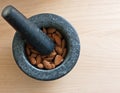 A mortar full of almonds with a pestle on top on a wooden table Royalty Free Stock Photo