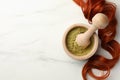 Mortar of henna powder and red strand on white marble table, flat lay with space for text. Natural hair coloring