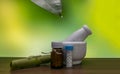 A mortar, homeopathic pills medicine bottles with rolled leaf and Homeopathic globule on the tip of a green leaf on green mix Royalty Free Stock Photo