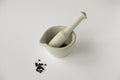 Mortar and pestle with black peppercorns on plain white background Royalty Free Stock Photo