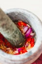 A mortar and pestle or lesung batu in Malay with crushed chilies, fried shallots and shrimp paste mixed together.