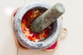 A mortar and pestle or lesung batu in Malay with crushed chilies, fried shallots and shrimp paste mixed together.