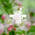 Mortar and pestle with ribbon in the centre of blurred background of leaves and pink flower.