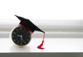 A mortarboard on an alarm clock in white background