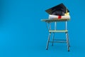 Mortarboard with certificate and school chair