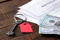 Mortgage application. Key with red keychain house and blank and money on a brown wooden table. concept of buying a home