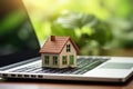 Mortgage concept with a house model on a laptop keyboard against a green nature background. Real estate, finance, and eco- Royalty Free Stock Photo