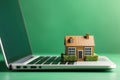 Mortgage concept with a house model on a laptop keyboard against a green nature background. Real estate, finance, and eco-