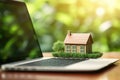 Mortgage concept with a house model on a laptop keyboard against a green nature background. Real estate, finance, and eco- Royalty Free Stock Photo