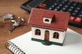 Mortgage concept. House model, notebook and calculator on wooden table, closeup Royalty Free Stock Photo